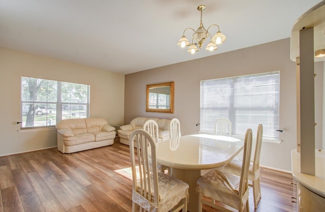 dining space with light hardwood / wood-style floors and a chandelier