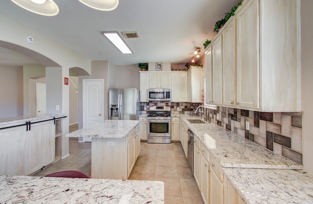 kitchen featuring light stone countertops, tasteful backsplash, stainless steel appliances, a kitchen island, and a breakfast bar area