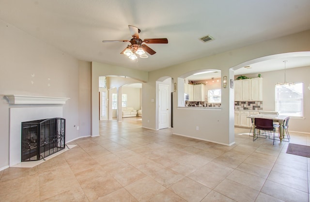 unfurnished living room with light tile patterned floors and ceiling fan with notable chandelier