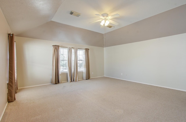 spare room with ceiling fan, light carpet, and vaulted ceiling