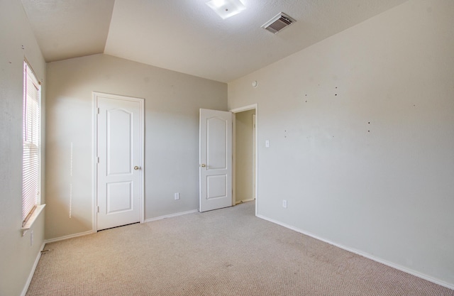 unfurnished bedroom featuring light carpet and lofted ceiling