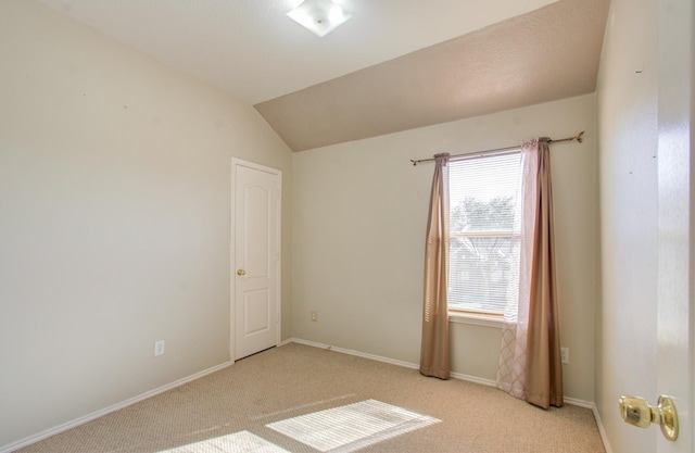 empty room featuring light carpet and vaulted ceiling