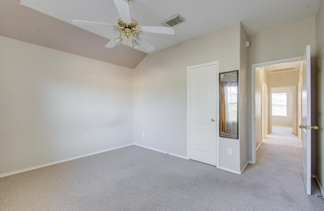 unfurnished bedroom with ceiling fan, a closet, light carpet, and vaulted ceiling