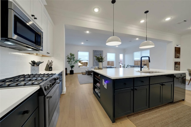 kitchen featuring stainless steel appliances, white cabinetry, sink, and hanging light fixtures