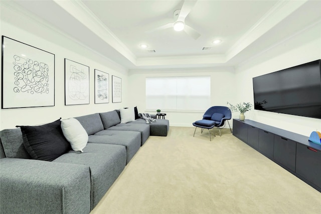 carpeted living room with ceiling fan, a tray ceiling, and crown molding