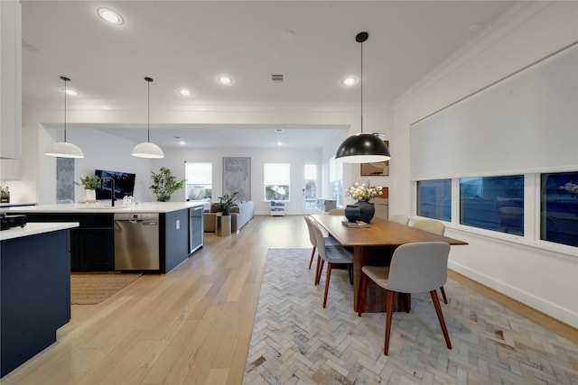 dining area with ornamental molding and light hardwood / wood-style floors