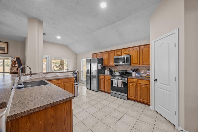 kitchen with appliances with stainless steel finishes, lofted ceiling, sink, backsplash, and a textured ceiling