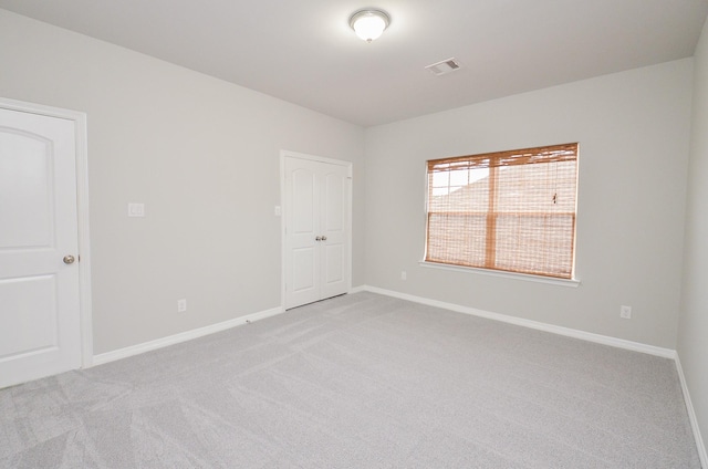 empty room featuring light colored carpet, visible vents, and baseboards