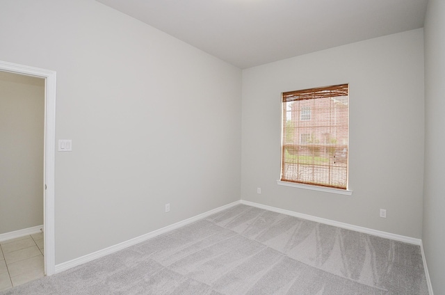 spare room with light tile patterned flooring, baseboards, and light colored carpet