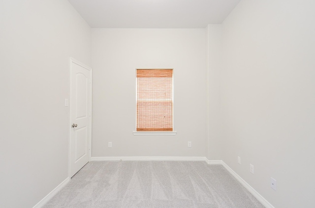 spare room featuring baseboards and light colored carpet