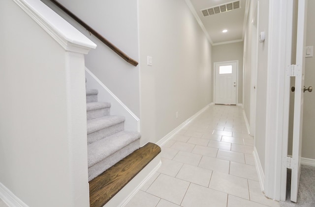 interior space featuring crown molding, visible vents, light tile patterned flooring, baseboards, and stairs