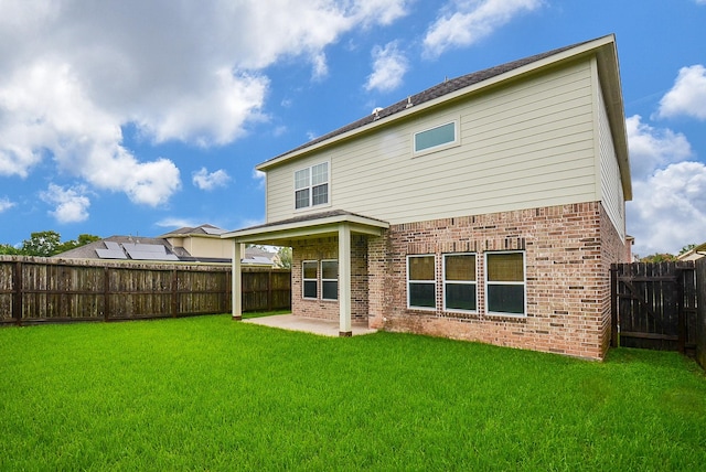 back of property with a patio area, brick siding, a lawn, and a fenced backyard