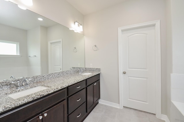 bathroom featuring double vanity, tile patterned flooring, a sink, and baseboards