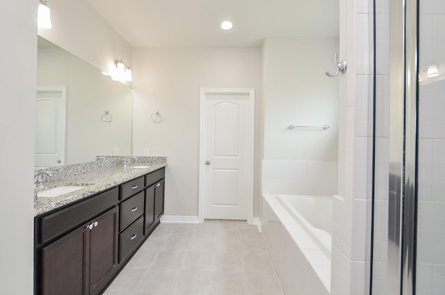 bathroom with double vanity, a garden tub, baseboards, and a sink