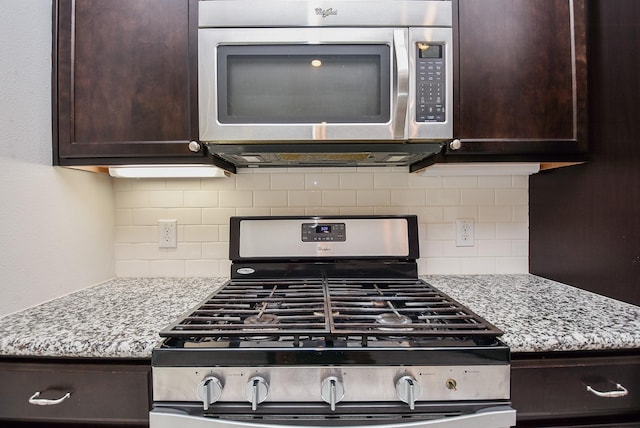 kitchen featuring light stone countertops, tasteful backsplash, stainless steel appliances, and dark brown cabinets