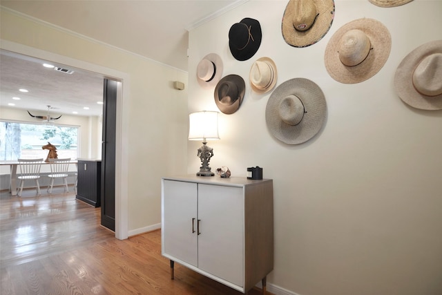 hallway with crown molding and light hardwood / wood-style flooring