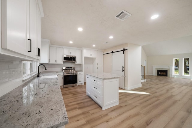 kitchen featuring a center island, white cabinets, sink, a barn door, and appliances with stainless steel finishes