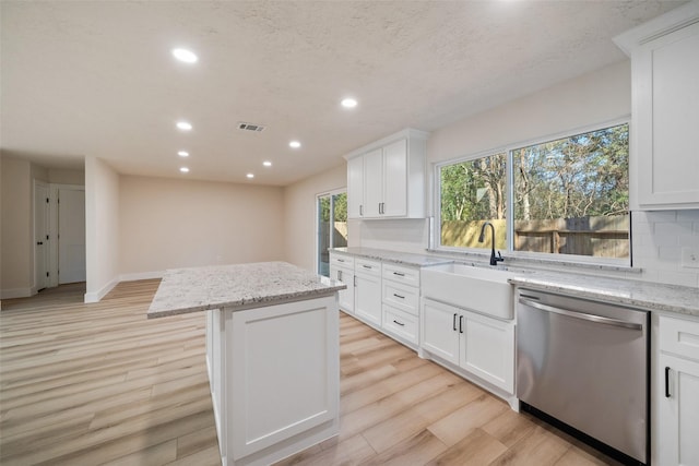 kitchen featuring dishwasher, a center island, white cabinets, and light stone countertops