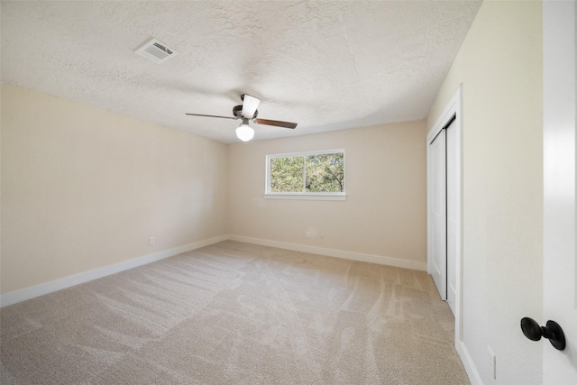 unfurnished bedroom featuring light carpet, a textured ceiling, and ceiling fan