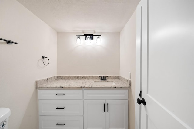 bathroom with a textured ceiling, vanity, and toilet