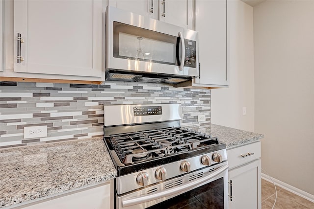 kitchen featuring light stone counters, white cabinetry, stainless steel appliances, and tasteful backsplash