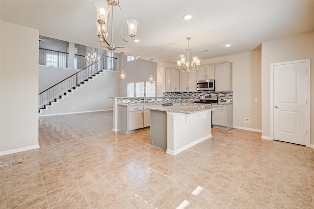 kitchen with a center island, light stone counters, pendant lighting, a breakfast bar, and appliances with stainless steel finishes