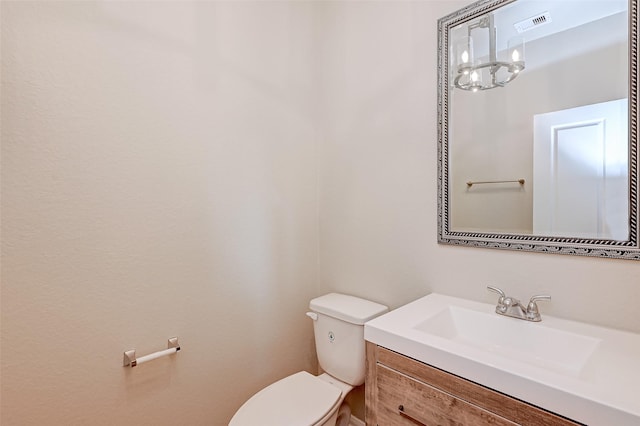 bathroom featuring an inviting chandelier, vanity, and toilet