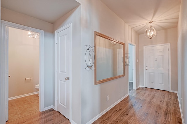 corridor featuring light hardwood / wood-style flooring and a notable chandelier