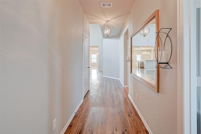 hallway with hardwood / wood-style floors and a notable chandelier