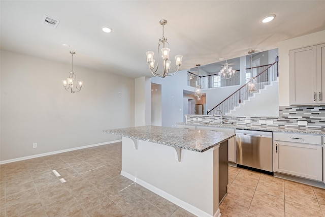 kitchen with a center island, white cabinetry, stainless steel dishwasher, and light stone counters