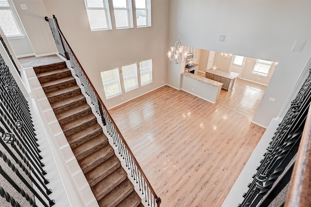 interior space with a high ceiling, light wood-type flooring, plenty of natural light, and a notable chandelier