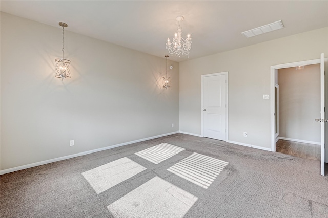 carpeted spare room featuring a notable chandelier