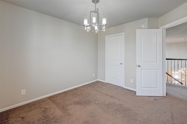 carpeted spare room featuring a chandelier