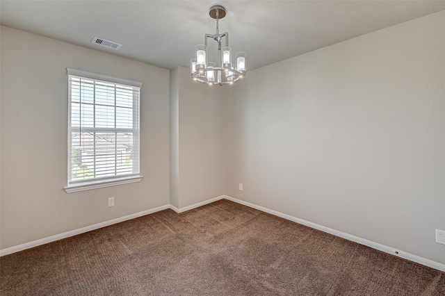 carpeted empty room featuring a notable chandelier