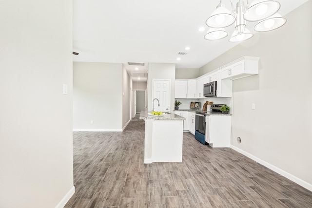 kitchen featuring a kitchen island with sink, sink, appliances with stainless steel finishes, light stone counters, and white cabinetry