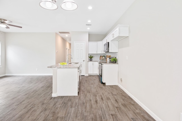 4649 Carmen St, Houston, TX 77051 - kitchen with appliances with stainless steel finishes, a sink, light wood-style flooring, white cabinets, and light stone countertops