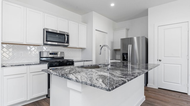 kitchen with appliances with stainless steel finishes, dark hardwood / wood-style flooring, sink, white cabinetry, and an island with sink