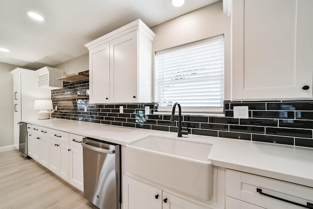 kitchen featuring white cabinets, dishwasher, decorative backsplash, and sink