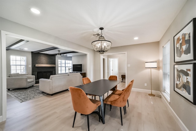 dining area featuring beam ceiling, light hardwood / wood-style floors, plenty of natural light, and a fireplace