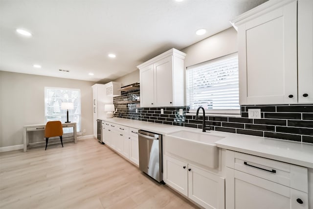 kitchen featuring decorative backsplash, stainless steel dishwasher, sink, light hardwood / wood-style floors, and white cabinetry