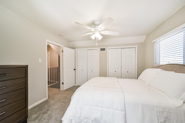 carpeted bedroom featuring ceiling fan and multiple closets