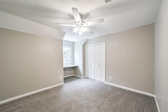 unfurnished bedroom with ceiling fan, a closet, and dark carpet