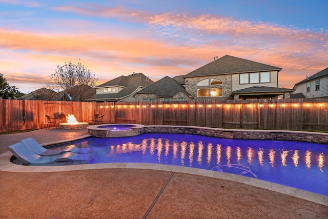 pool at dusk featuring a patio area, an in ground hot tub, and an outdoor fire pit