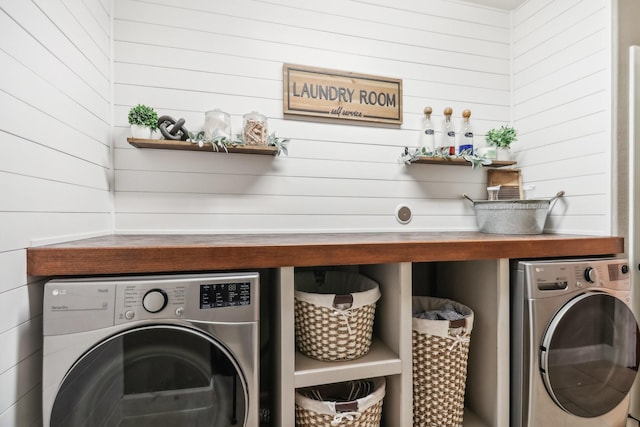 laundry room with separate washer and dryer and wood walls