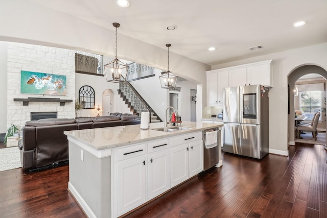 kitchen featuring an island with sink, a fireplace, white cabinets, and stainless steel appliances