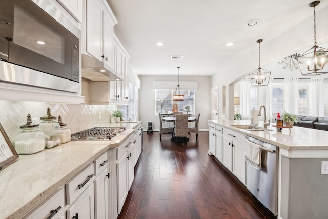 kitchen with decorative light fixtures, sink, white cabinetry, and stainless steel appliances