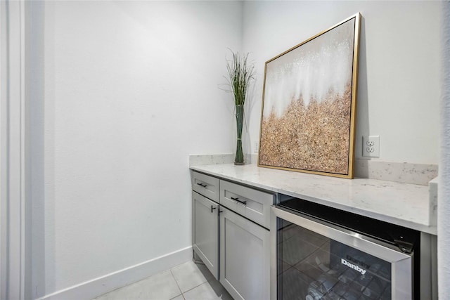 interior space featuring gray cabinets, light tile patterned flooring, wine cooler, and light stone counters