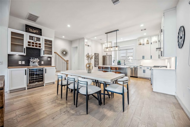 dining room with beverage cooler and light hardwood / wood-style flooring