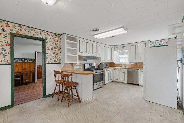 kitchen featuring sink, stainless steel appliances, a kitchen breakfast bar, wooden counters, and white cabinets