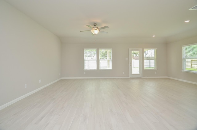 empty room featuring a healthy amount of sunlight, ceiling fan, and light hardwood / wood-style floors